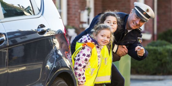 Ein Polizeibeamter übt mit Kindern das sichere Verhalten im Straßenverkehr